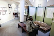 Professor Clarence Glover sits in front of a representation of a grave and the display of...
