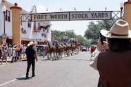 People take photos as the Budweiser Clydesdales pass under the Fort Worth Stockyards sign...