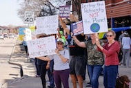 People hold signs along Main Street during a protest against Rep. Pat Fallon and President...