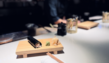 A handroll sitting on a plate on an elegant black bar.