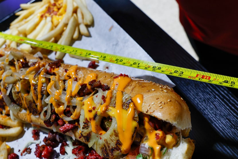 El Reyno Taqueria owner Jose Reyna holds up a measuring tape alongside a two-foot long hot...