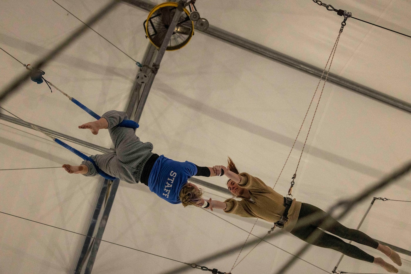 Peyton Moody (left), trainer, swings in a catch lock while grabbing hands with Kaitlyn...