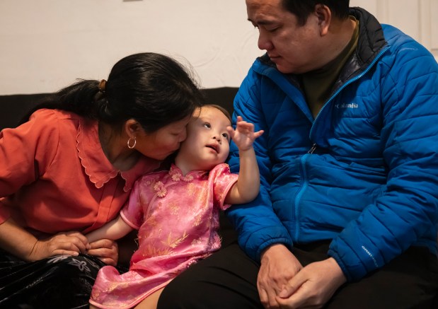 Thi Dua Vang kisses her one-year-old granddaughter, Pang Chia, as she and her husband, A Pao Giang, speak with journalists at an undisclosed location.