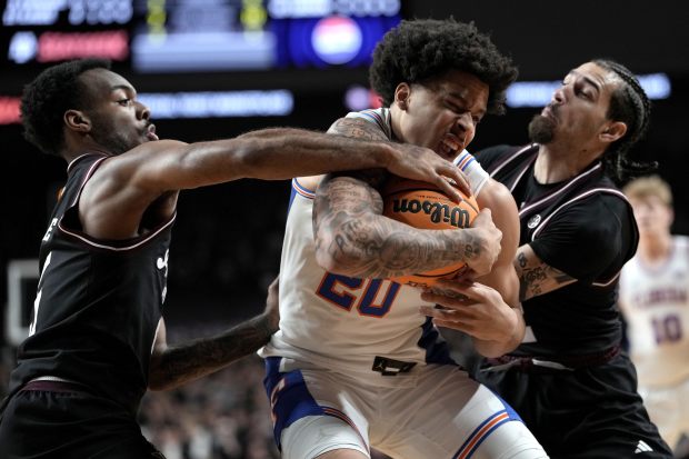Florida guard Isaiah Brown, center, fights for a rebound against Texas A&M guard Jacari Lane, left, and guard Pop Isaacs, right, of an NCAA college basketball game Saturday, Feb. 7, 2026, in College Station, Texas. (AP Photo/Sam Craft)