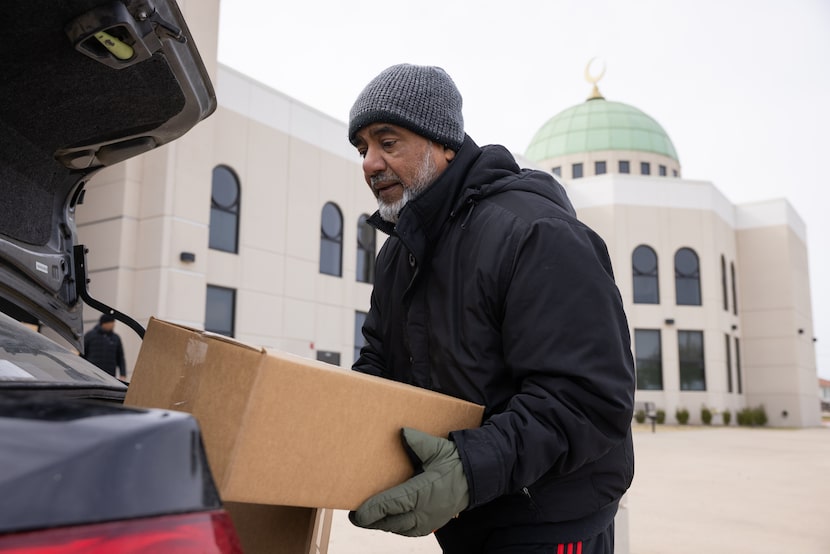 Volunteer Mohamed Habib loads a box of food into a vehicle during the Help Your Neighbor...