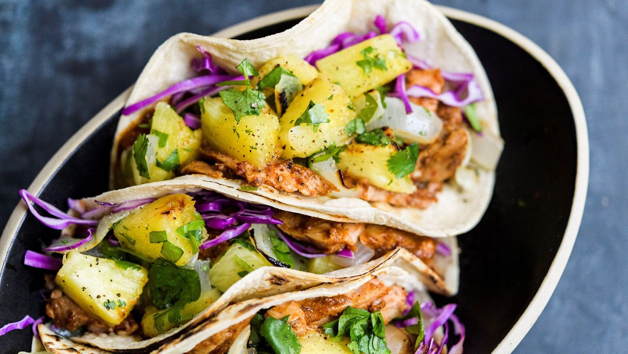 This image released by Milk Street shows a recipe for tacos made with broiled pork tenderloin tenderized with fresh pineapple. (Milk Street via AP)