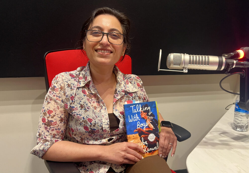 Tayyba Kanwal holding her book in a radio studio
