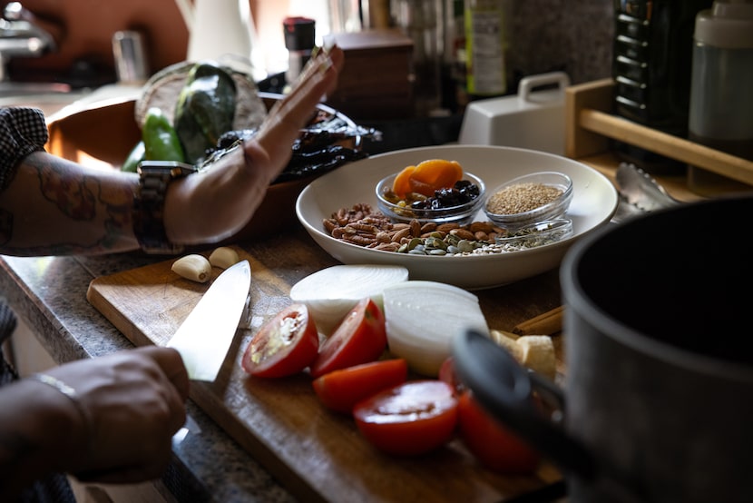 Chef Anastacia Quiñones-Pittman crushes garlic with the flat side of a kitchen knife before...