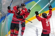 Canada's Nathan MacKinnon (29) celebrates with Sam Reinhart (13) and Macklin Celebrini (17)...