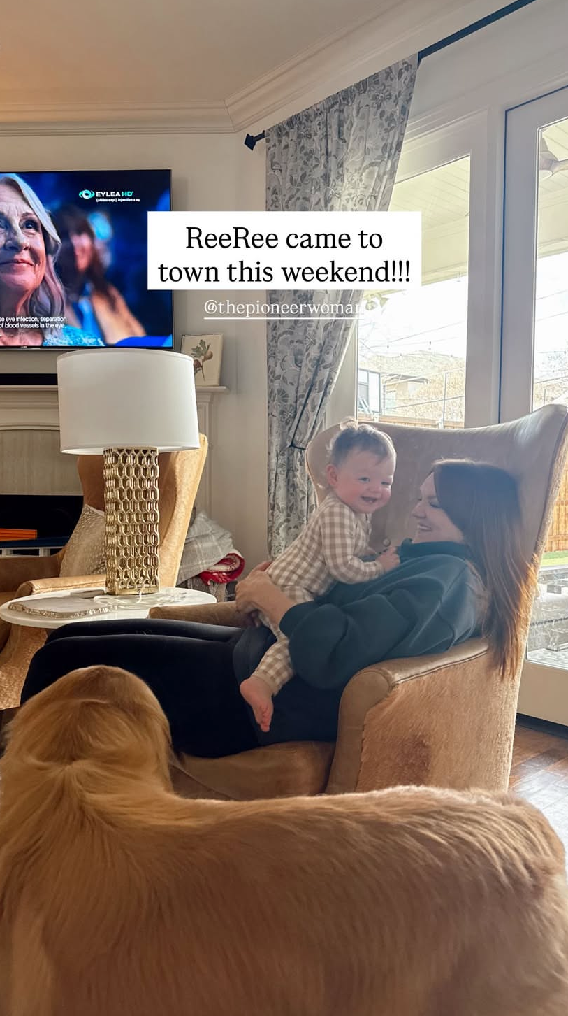 ree drummond sitting in a cozy living room with a child on her lap and a dog nearby