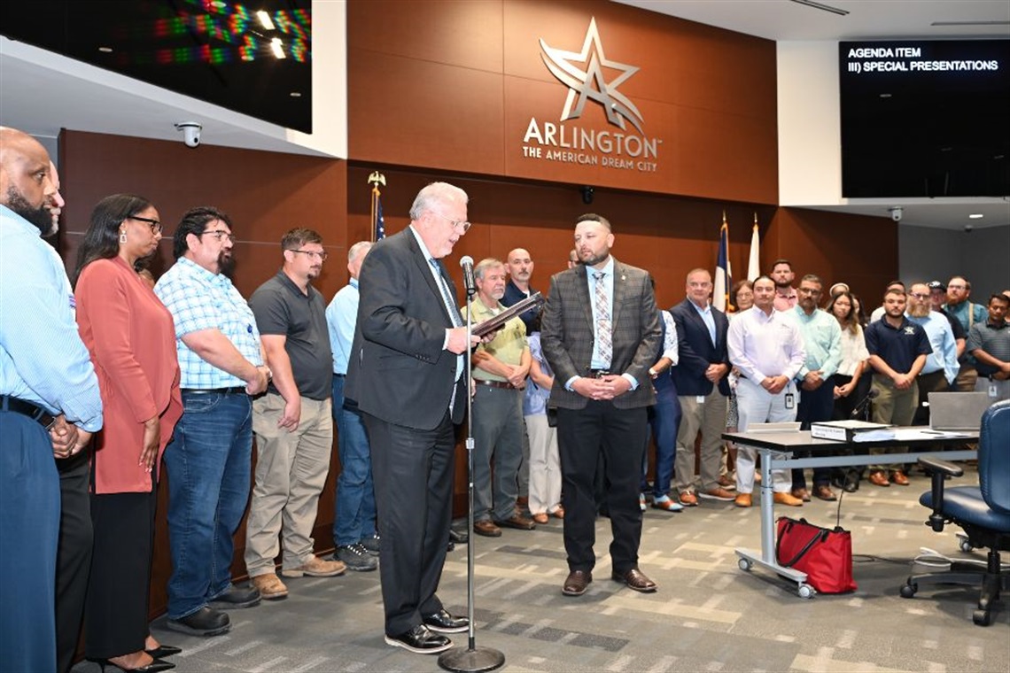 A group of people standing in Arlington City Council Chambers receiving a recognition.