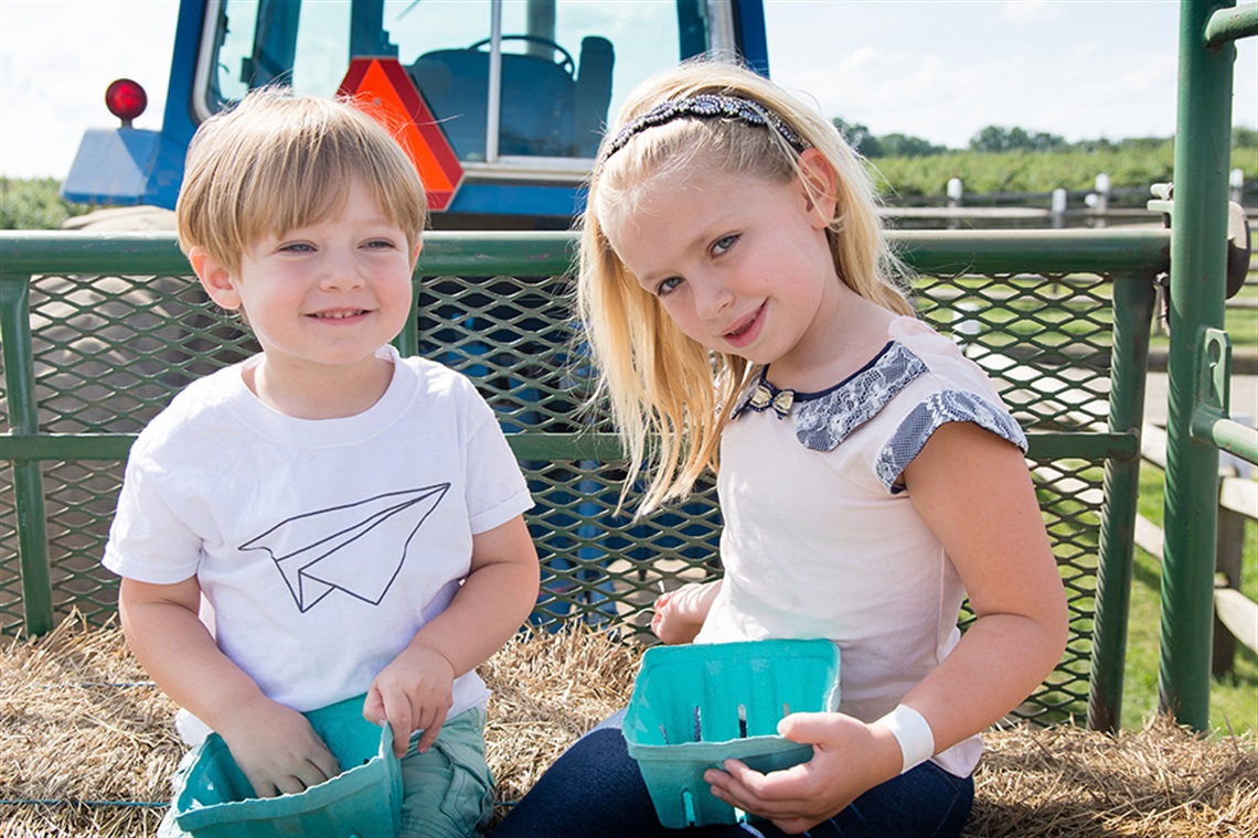 Siblings riding hay ride on tractor together.