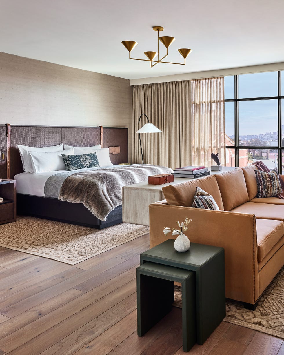 luxury hotel room featuring plush bed and brown leather couch