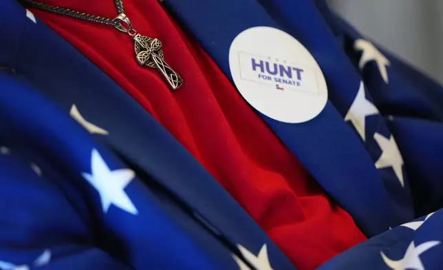 Roger Phillips, left, wears a United States flag inspired outfit as he listens to U.S. Rep. Wesley Hunt, R-Texas, speak at a campaign event, Monday, Feb. 16, 2026, in Dallas. (AP Photo/Julio Cortez)