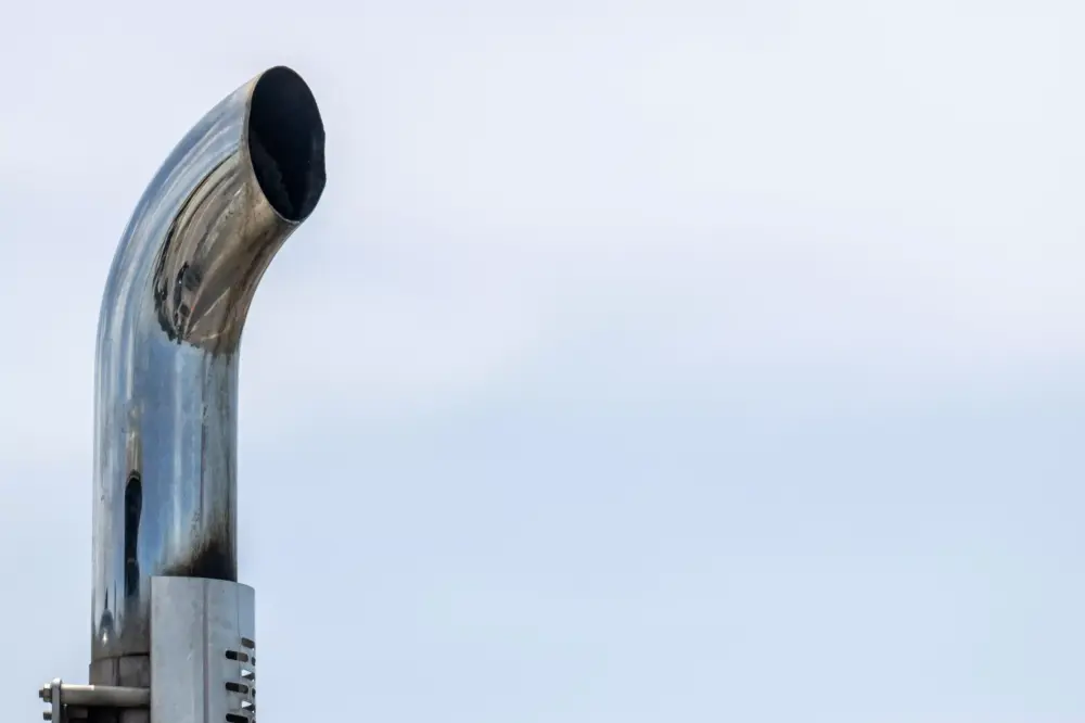 This photo is a close-up of a shiny metal exhaust pipe atop a truck in Austin, Texas.