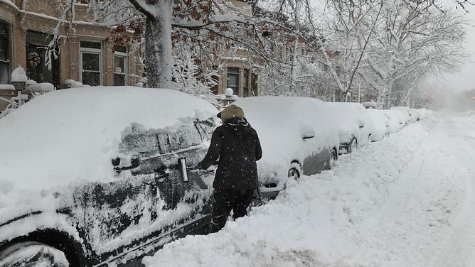 A driver clears snow off a vehicle during a winter storm in the Brooklyn borough of New York, US, on Monday, Feb. 23, 2026.