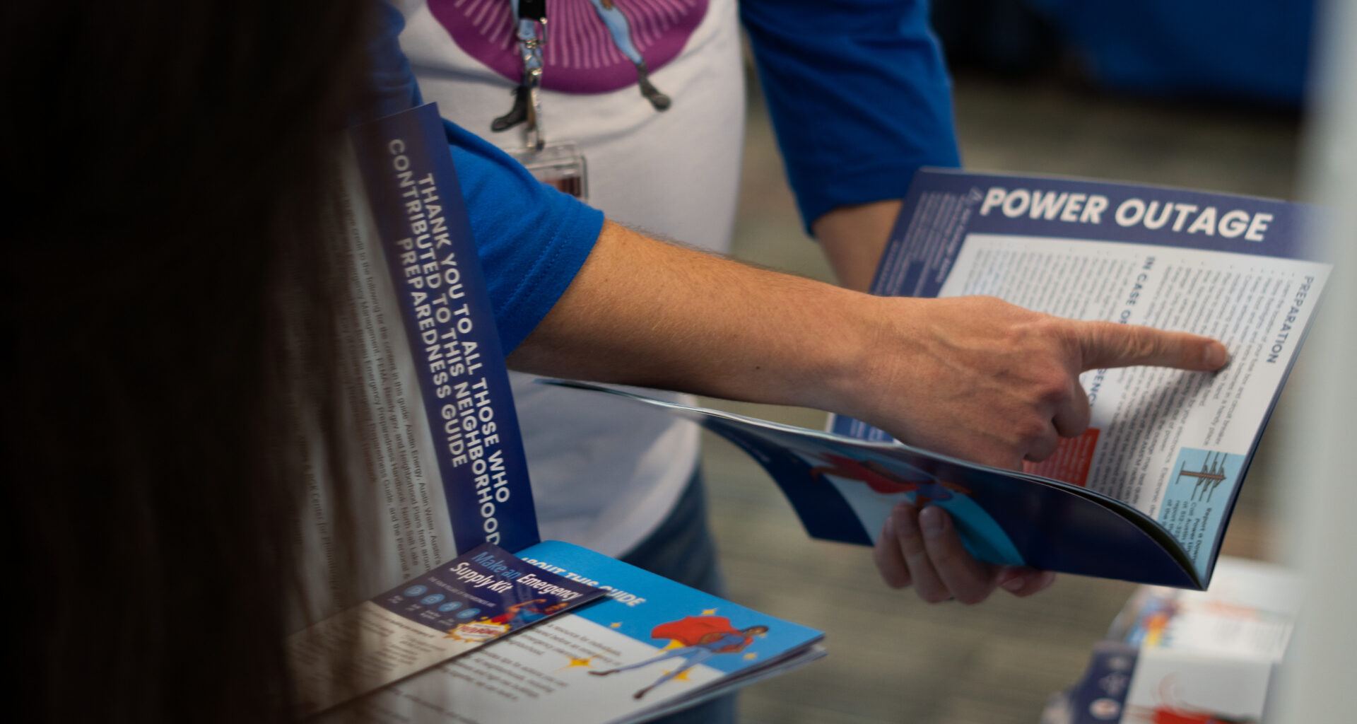 photo of a hand pointing to preparedness information regarding power outages in a booklet