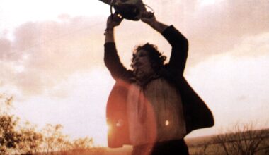 Leatherface (Gunnar Hansen) holds a chainsaw above his head in The Texas Chain Saw Massacre (1974).