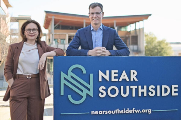 Arts professionals Megan Henderson and Mike Brennan stand outside behind a placard that reads "Near Southside."