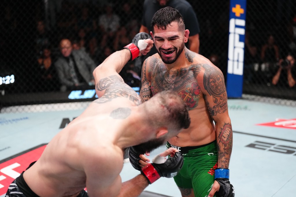 Two shirtless, tattooed male fighters in a UFC cage, one landing a punch to the other's face.
