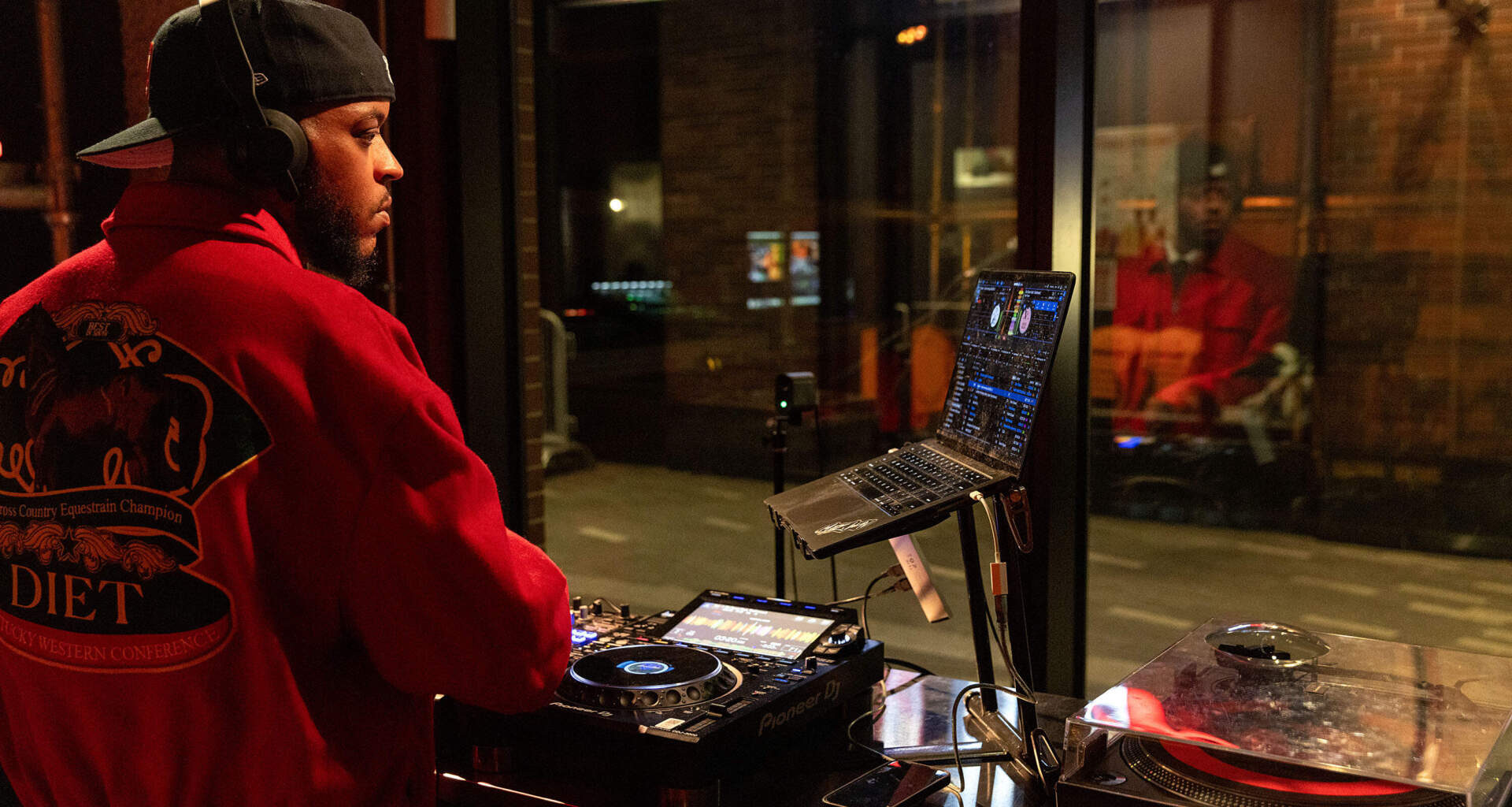 People walk along Massachusetts Ave. as DJ Mars Jptr streams from the studio of Central on Air in Cambridge, Mass. (Robin Lubbock/WBUR)