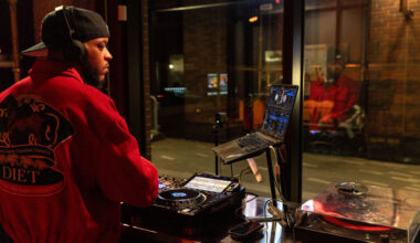 People walk along Massachusetts Ave. as DJ Mars Jptr streams from the studio of Central on Air in Cambridge, Mass. (Robin Lubbock/WBUR)