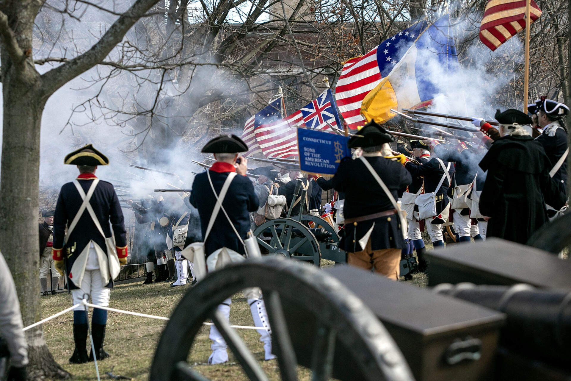 Reenactors on Dorchester Heights fire their muskets in the direction of Boston during the commemoration for the 250th anniversary Evacuation Day, marking the end of the siege of Boston. (Robin Lubbock/WBUR)
