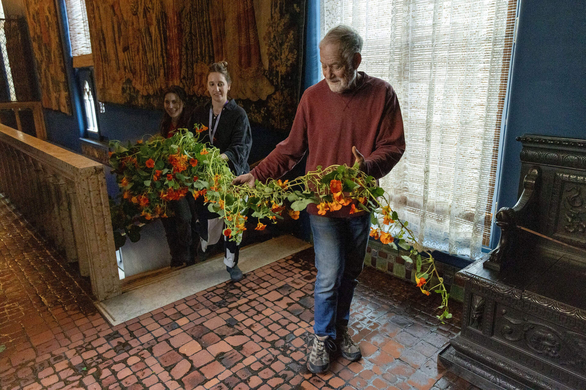 Members of the museum’s horticulture team and volunteers carry a nasturtium vine up the to the third floor of the Isabella Stewart Gardner Museum. (Robin Lubbock/WBUR)