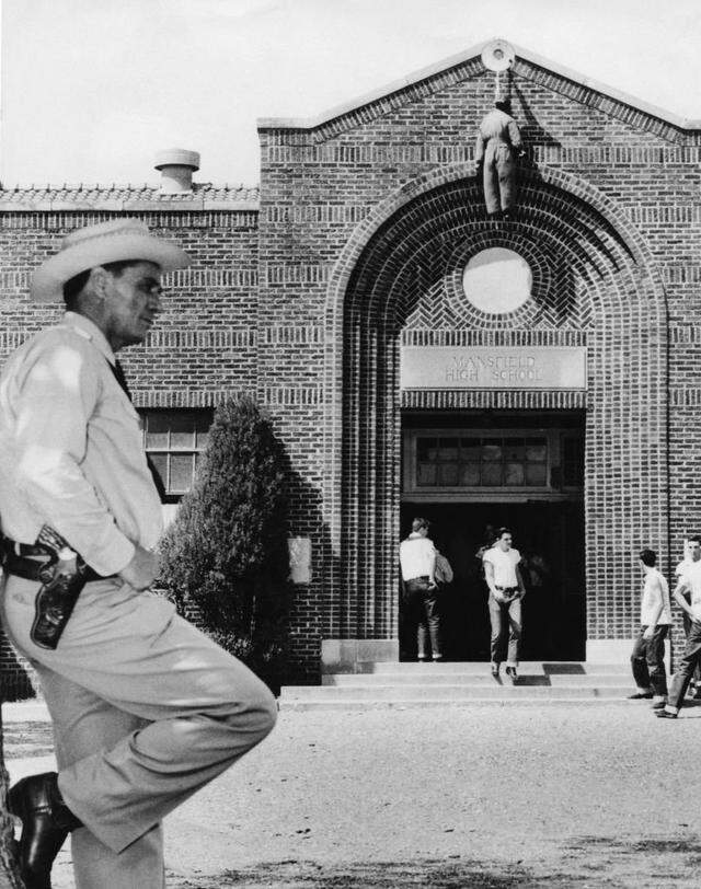 To protest against having Black students register for Mansfield High School, an effigy is suspended above the school entrance with Texas Rangers Sgt. Jay Banks on hand to maintain calm on Nov. 23, 1956.