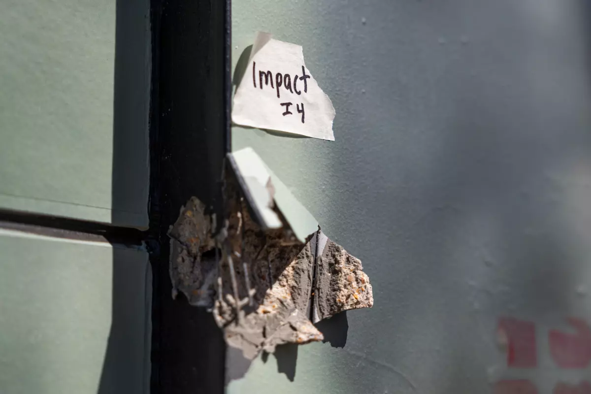 An evidence tag is shown above part of a wall damaged from the shooting on West Sixth Street.