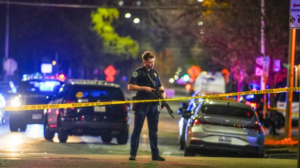 An Austin police officer guards the scene on West 6th Street at West Avenue after a shooting,...