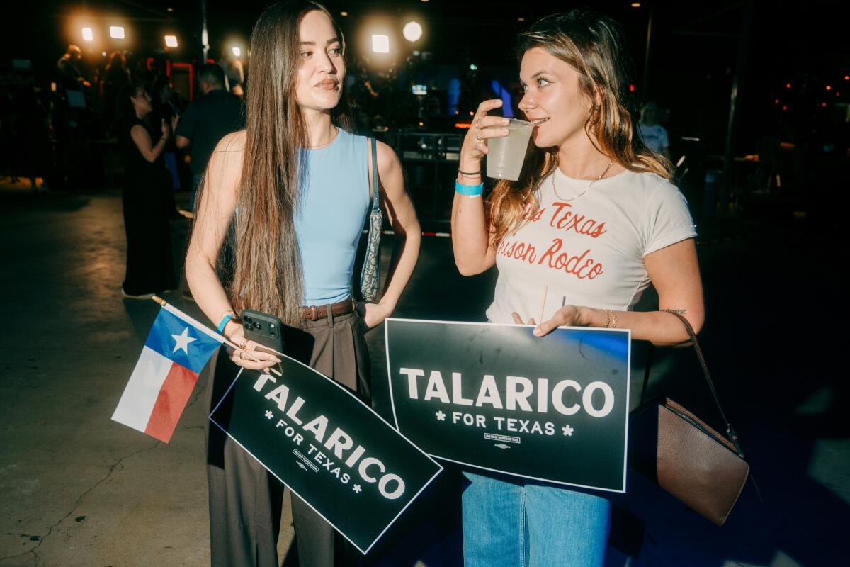 Two women stand together with Talarico signs.