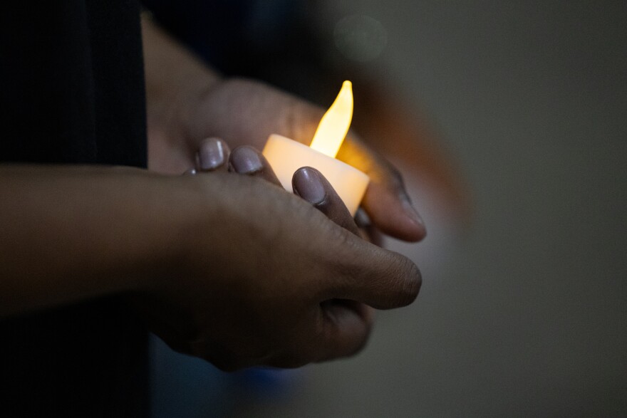 A woman holds a candle during a vigil.