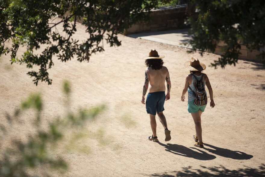 Two people wearing sun hats walk along the Hike and Bike Trail at Vic Mathias Shores  