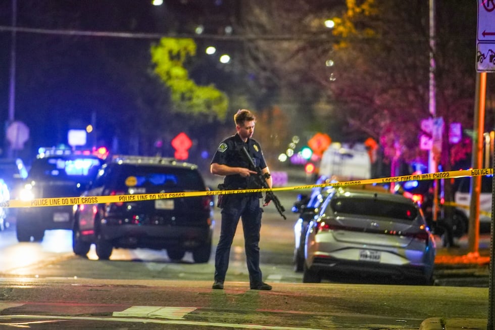 An Austin police officer guards the scene on West 6th Street at West Avenue after a shooting,...