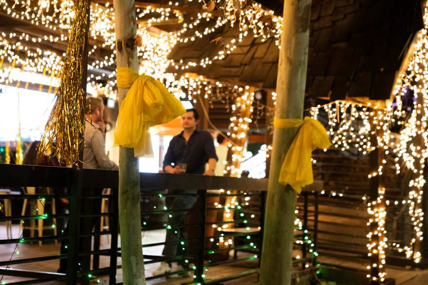 Yellow ribbon hangs from trees outside of a bar.