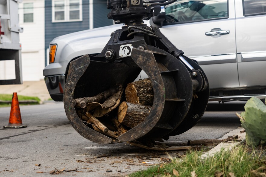 A claw like machine picks up a stack of wood. 