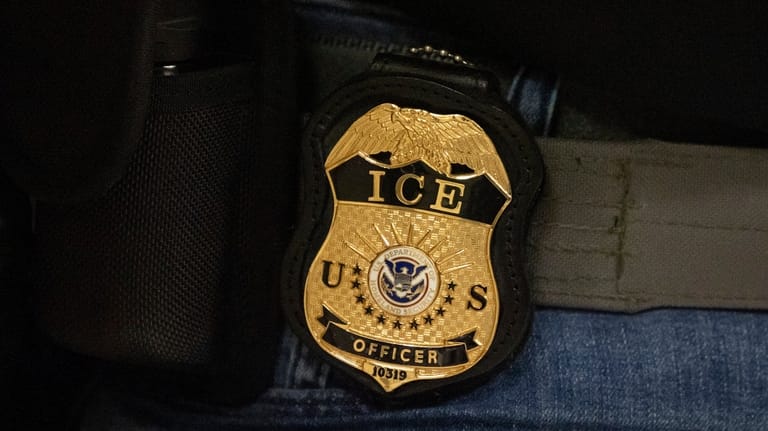 A federal agent wears an Immigration and Customs Enforcement badge...