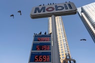 Birds fly around a sign showing the gas prices at a gas station, Tuesday, March 10, 2026, in...