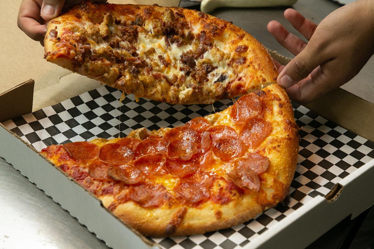 Kylie Painter, a pizzaiolo at Authentic New York Pizza, slices up a chicken Alfredo pizza on Feb. 8, 2023.