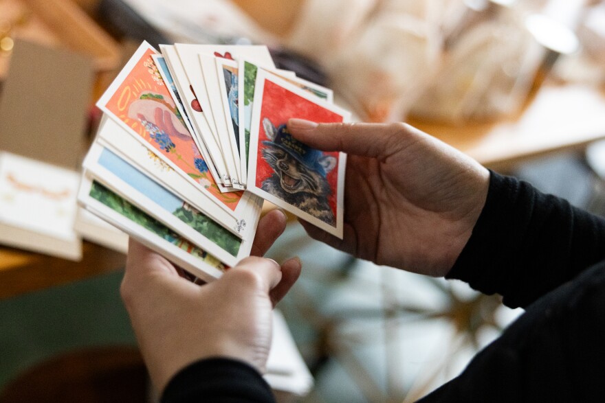 A set of small cards which are mini-paintings are shown in someone's hands.