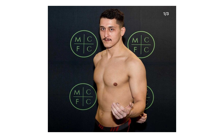 Jorge Pederson poses for a photo in front of a black background with the words MCFC.