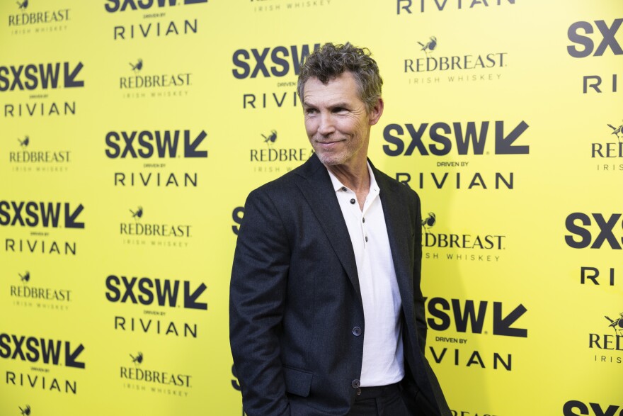 Shawn Hatosy poses for photos in front of a yellow backdrop with SXSW logos.