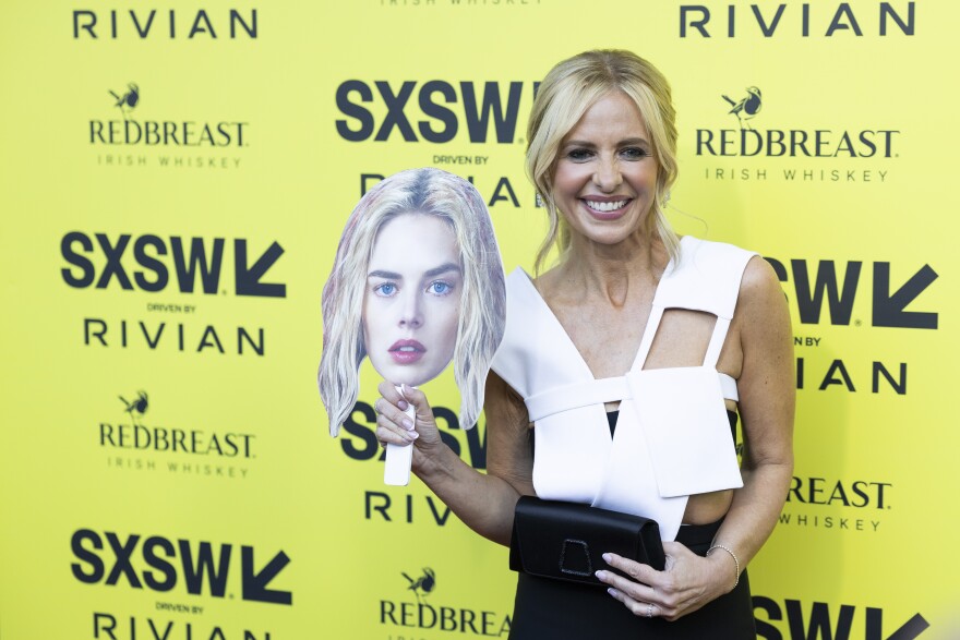 Sarah Michelle Gellar poses for photos with a cutout of lead actress Samara Weaving in front of a yellow backdrop with SXSW logos on it.