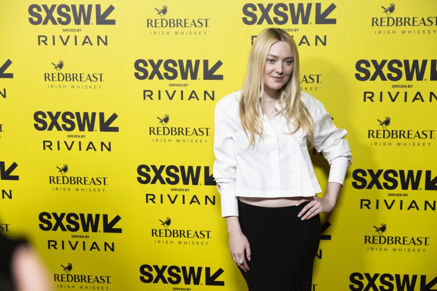 Dakota Fanning poses for photos in front of a yellow backdrop with SXSW logos on it.