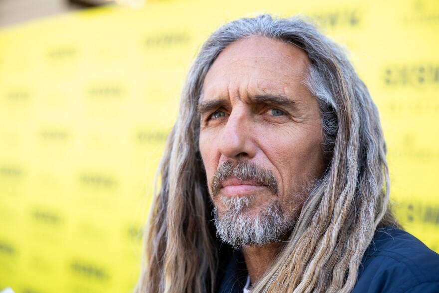 Rob Machado stands in front of a yellow backdrop.