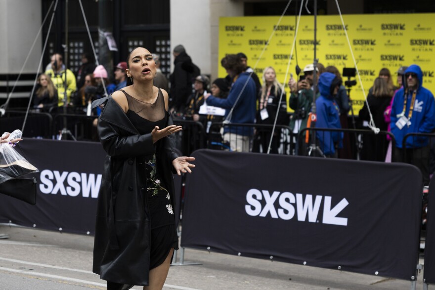 Alexandra Shipp reacts to the cold weather while walking down a street lined with SXSW barricades.