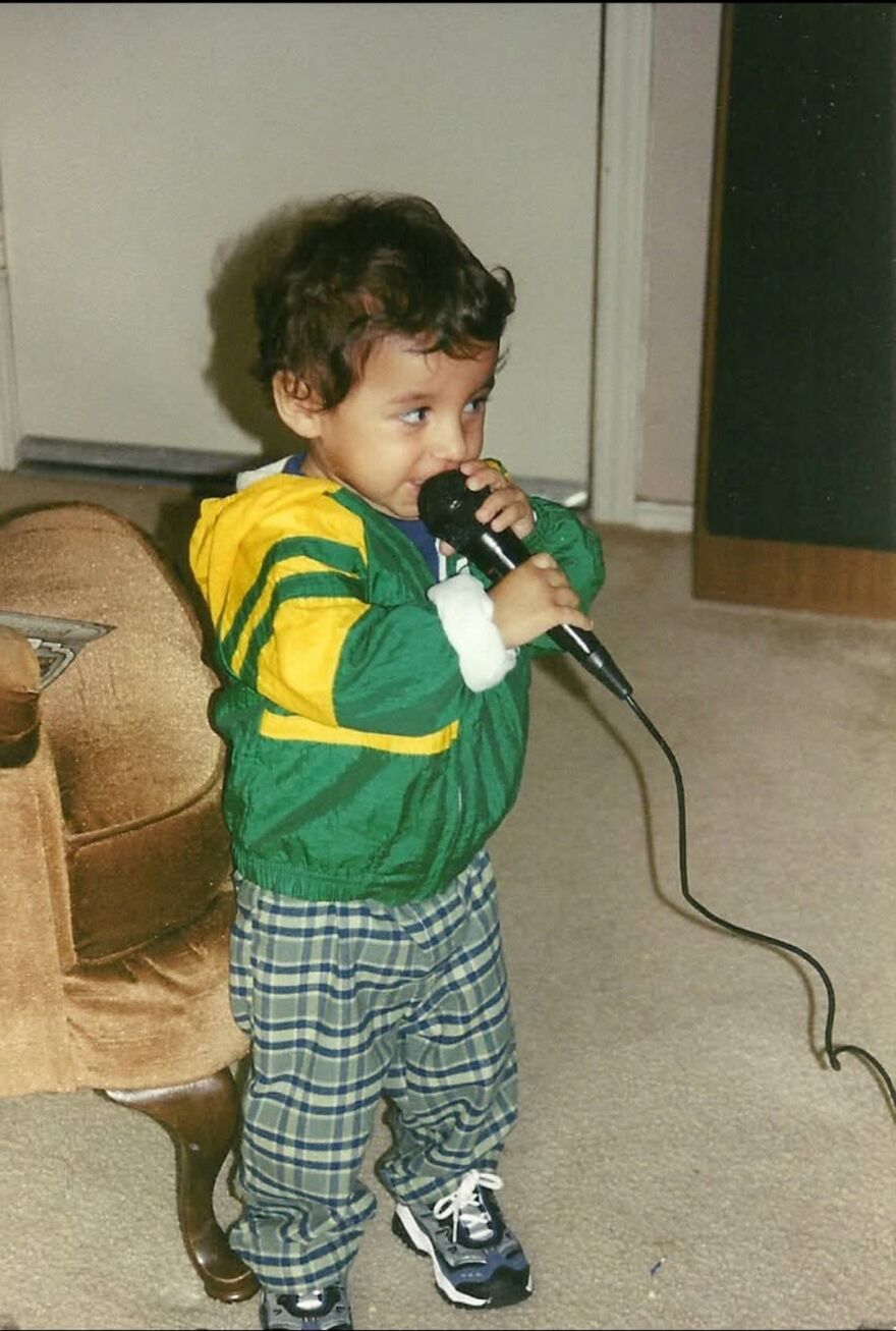 A toddler holds a microphone up to his mouth.