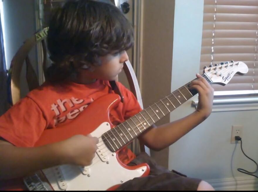 A young boy holds an electric guitar.