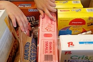 In this file photo, a volunteer puts groceries into a box for clients at Crossroads...